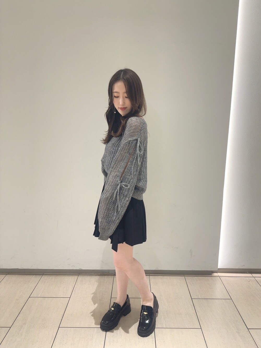 グレー系のニット/セーター、ブラック系のスカート、ブラック系のシューズを着用したレディースの夏コーディネートの3枚目の写真