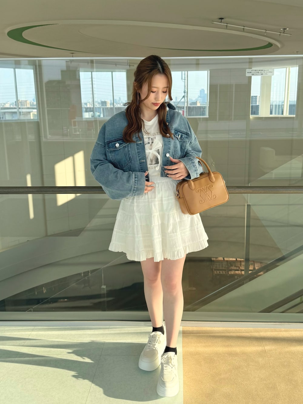 ホワイト系のスニーカー、ホワイト系のスカート、ブルー系のデニムジャケットを着用したレディースの春コーディネートの2枚目の写真