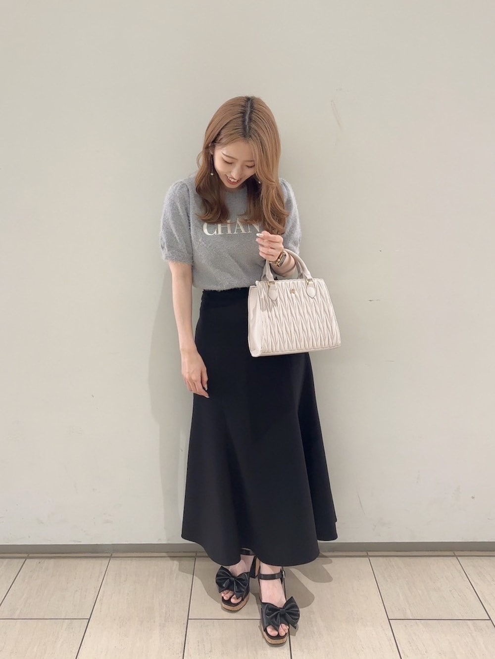 グレー系のニット/セーター、ブラック系のスカート、ブラック系のサンダルを着用したレディースの夏コーディネートの2枚目の写真