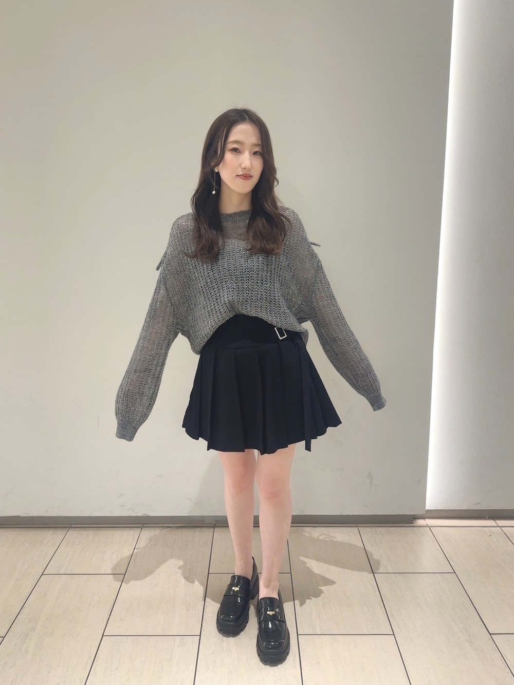 グレー系のニット/セーター、ブラック系のスカート、ブラック系のシューズを着用したレディースの夏コーディネートの2枚目の写真