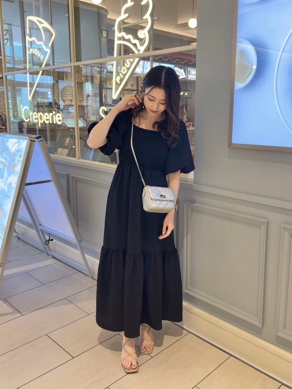 シルバー系のショルダーバッグ、ブラック系のワンピースを着用したレディースの夏コーディネートの2枚目の写真