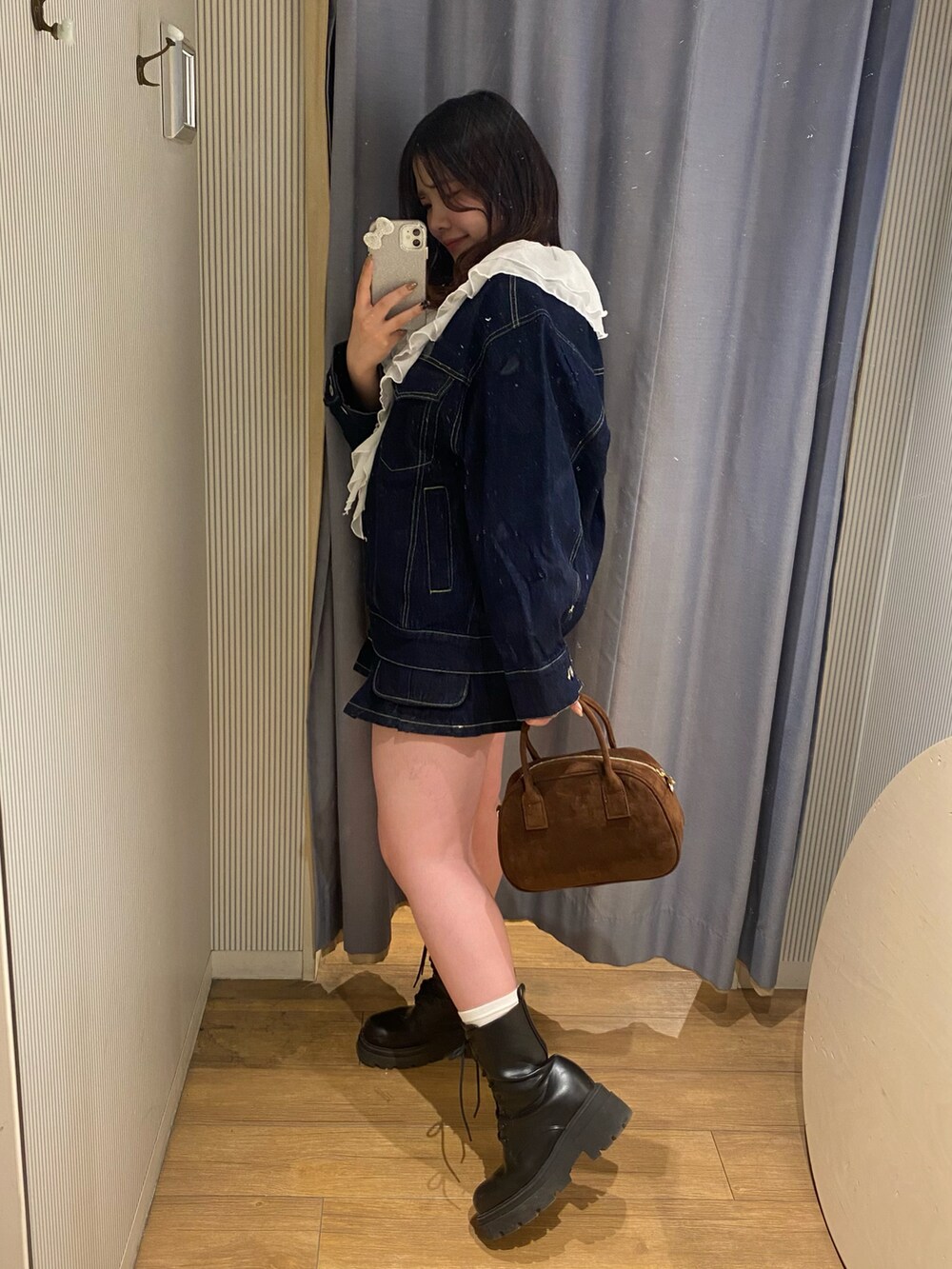 ブルー系のデニムジャケット、ブルー系のデニムスカート、ブラウン系のバッグを着用したレディースの冬コーディネートの3枚目の写真