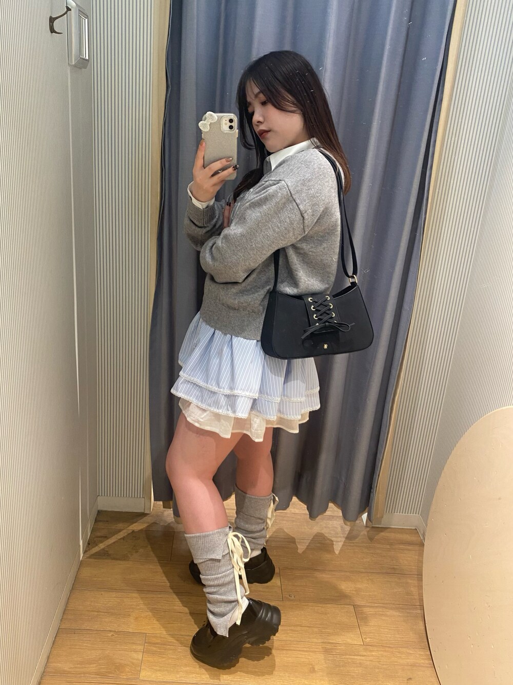 グレー系のニット/セーター、ブルー系のチュニック、ブラック系のショルダーバッグを着用したレディースの冬コーディネートの2枚目の写真