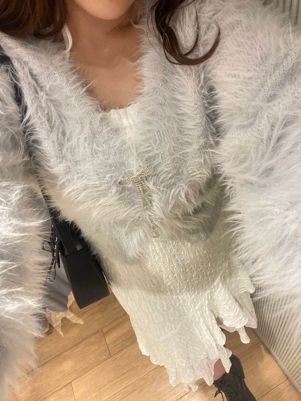 ブルー系のカーディガン/ボレロ、ホワイト系のワンピース、ブラック系のショルダーバッグを着用したレディースの冬コーディネートの2枚目の写真