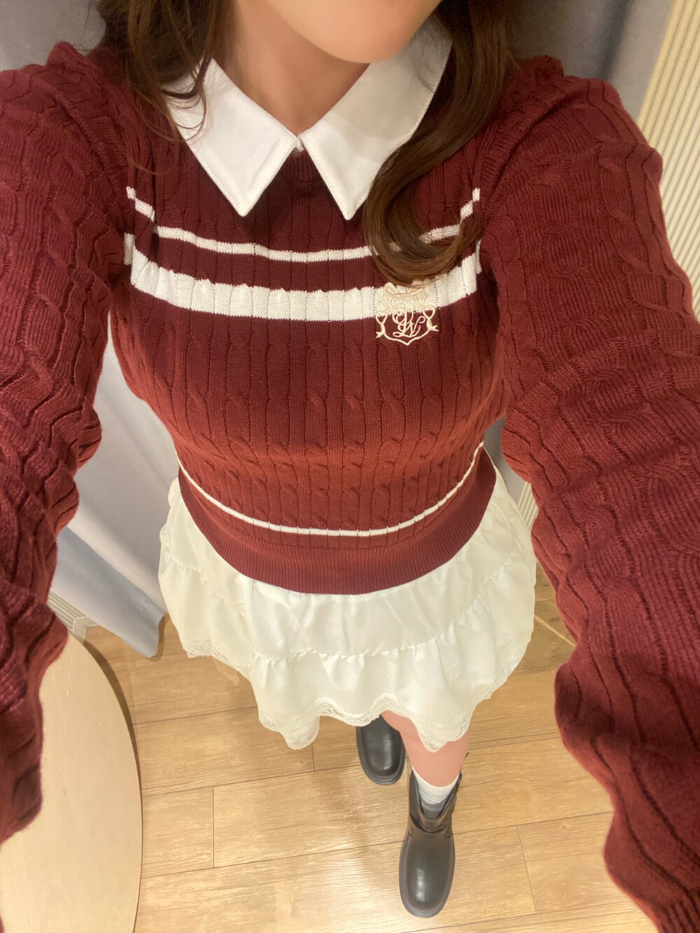 レッド系のニット/セーター、ホワイト系のスカート、ブラック系のブーツを着用したレディースの冬コーディネートの3枚目の写真