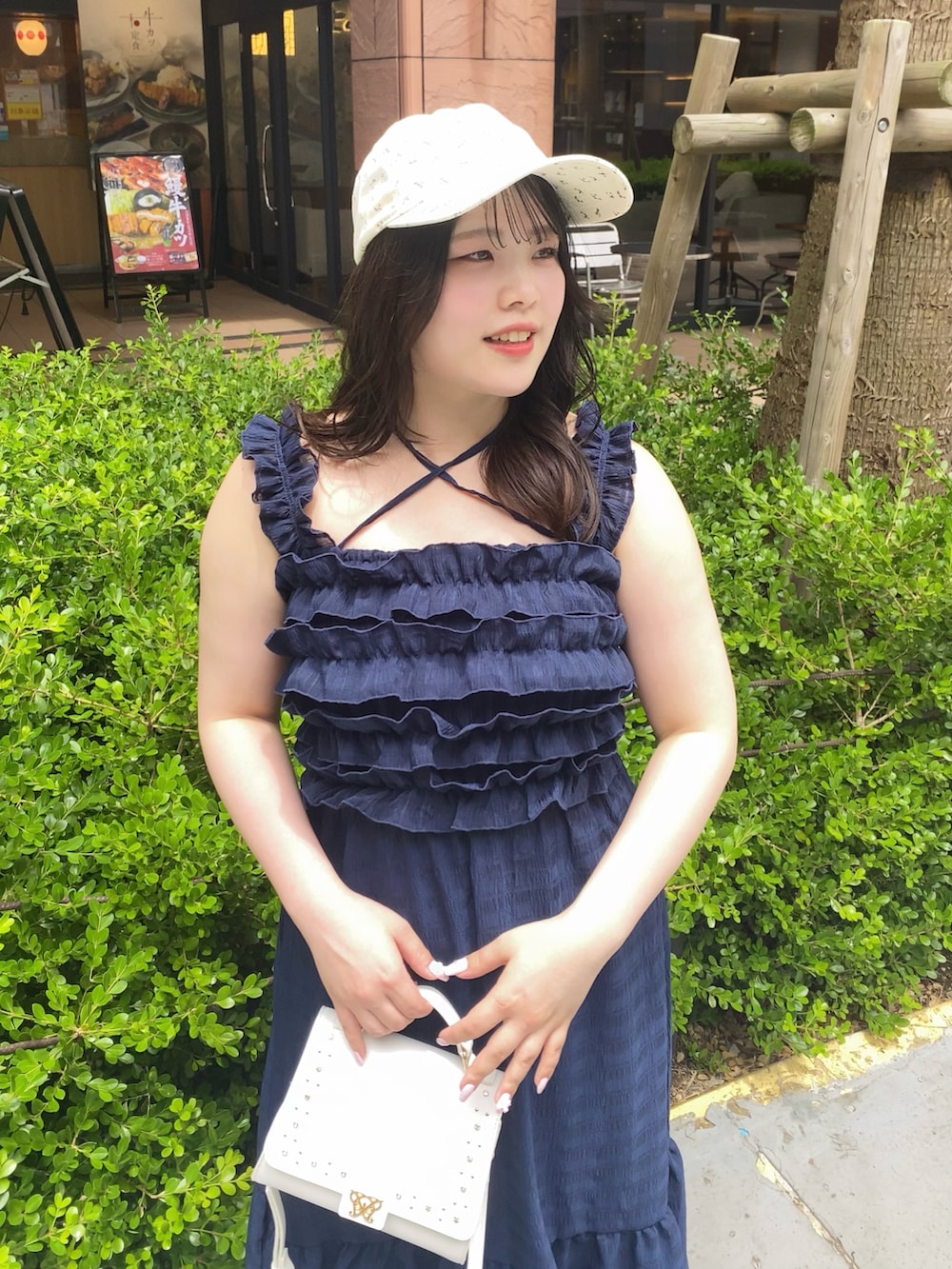 ブルー系のワンピース、ホワイト系のサンダル、ホワイト系のキャップを着用したレディースの夏コーディネートの2枚目の写真