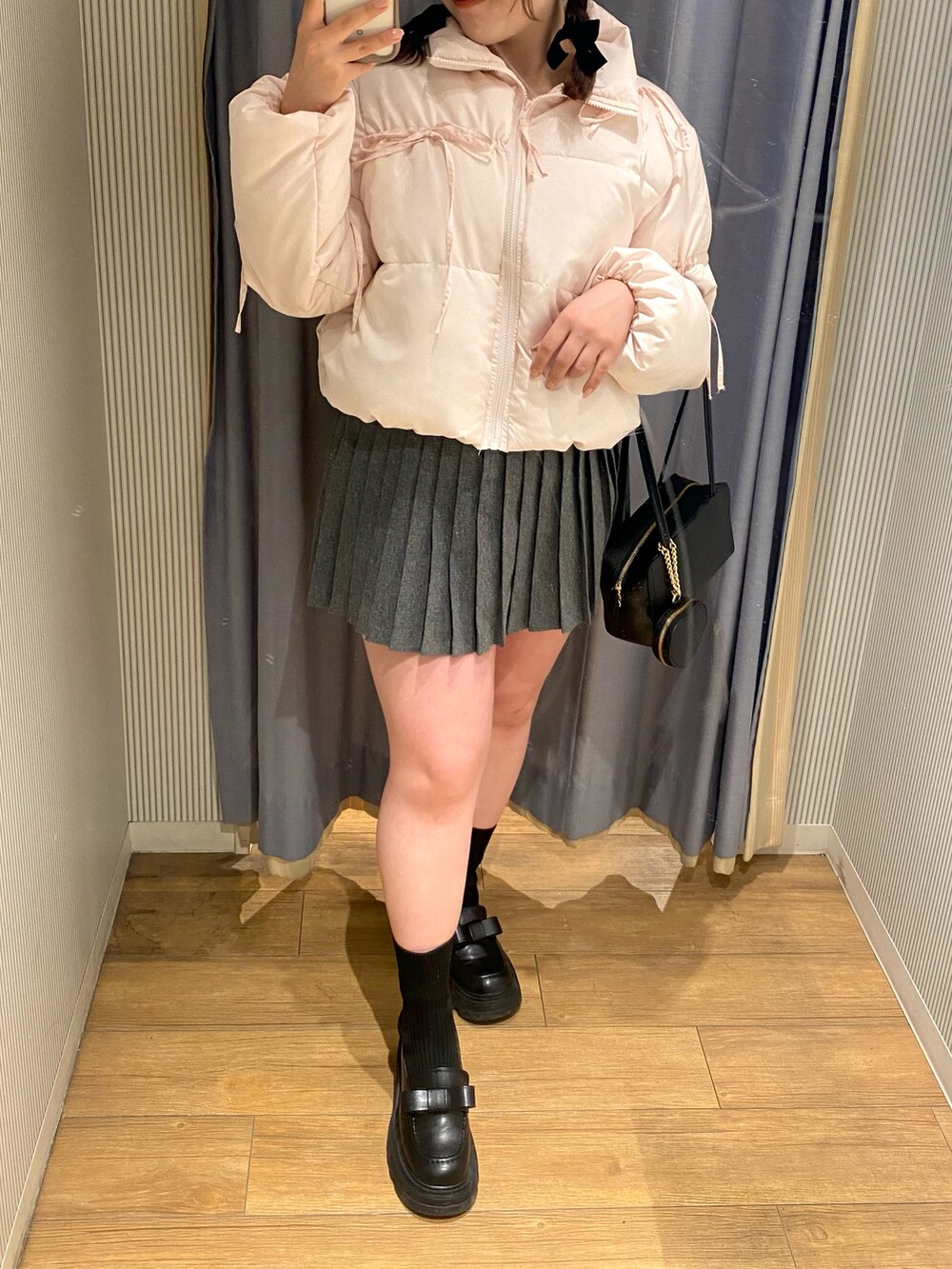 ピンク系のダウンジャケット/コート、グレー系のスカート、ブラック系のショルダーバッグを着用したレディースの冬コーディネートの2枚目の写真