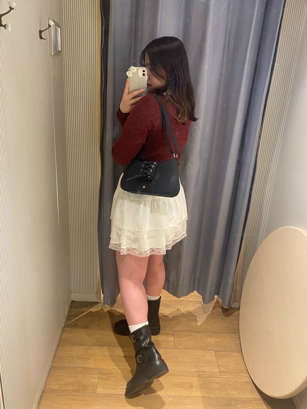 レッド系のニット/セーター、ホワイト系のスカート、ブラック系のブーツを着用したレディースの冬コーディネートの2枚目の写真