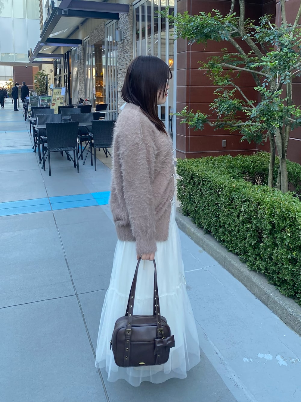 ブラウン系のカーディガン/ボレロ、ホワイト系のスカート、ブラウン系のショルダーバッグを着用したレディースの冬コーディネートの2枚目の写真