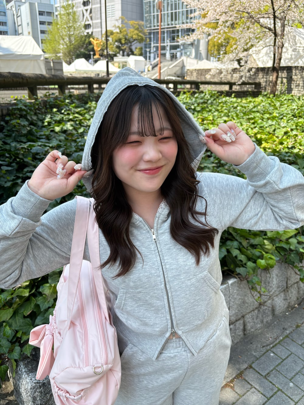 グレー系のパーカー、グレー系のスウェットパンツ、ピンク系のボストンバッグを着用したレディースの春コーディネートの2枚目の写真