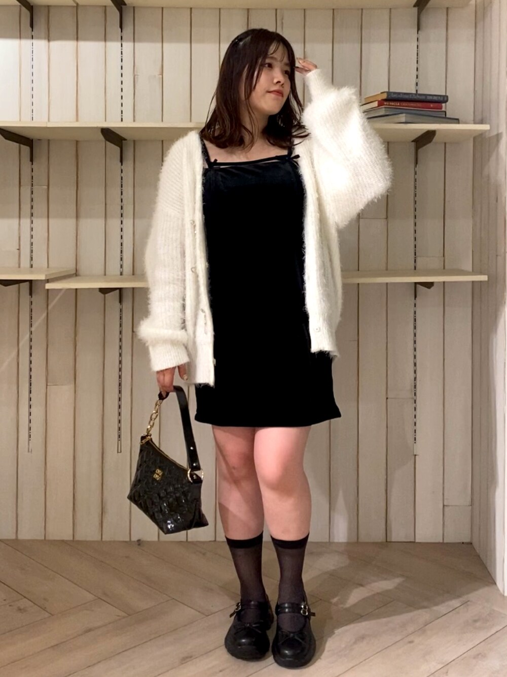 ホワイト系のカーディガン/ボレロ、ブラック系のワンピース、ブラック系のショルダーバッグを着用したレディースの秋コーディネートの2枚目の写真