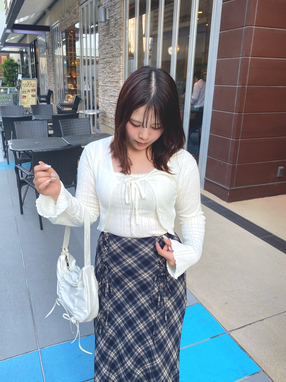 ホワイト系のアンサンブル、ブルー系のスカート、ブラック系のブーツを着用したレディースの秋コーディネートの2枚目の写真