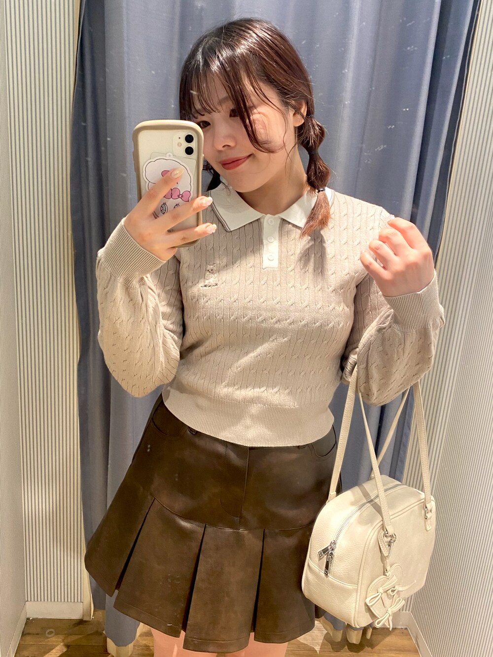 ブラウン系のスカート、ホワイト系のショルダーバッグ、ブラウン系のブーツを着用したレディースの秋コーディネートの2枚目の写真