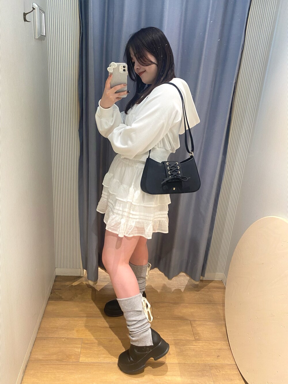 ブラック系のショルダーバッグ、ホワイト系のパーカー、ホワイト系のスカートを着用したレディースの冬コーディネートの2枚目の写真