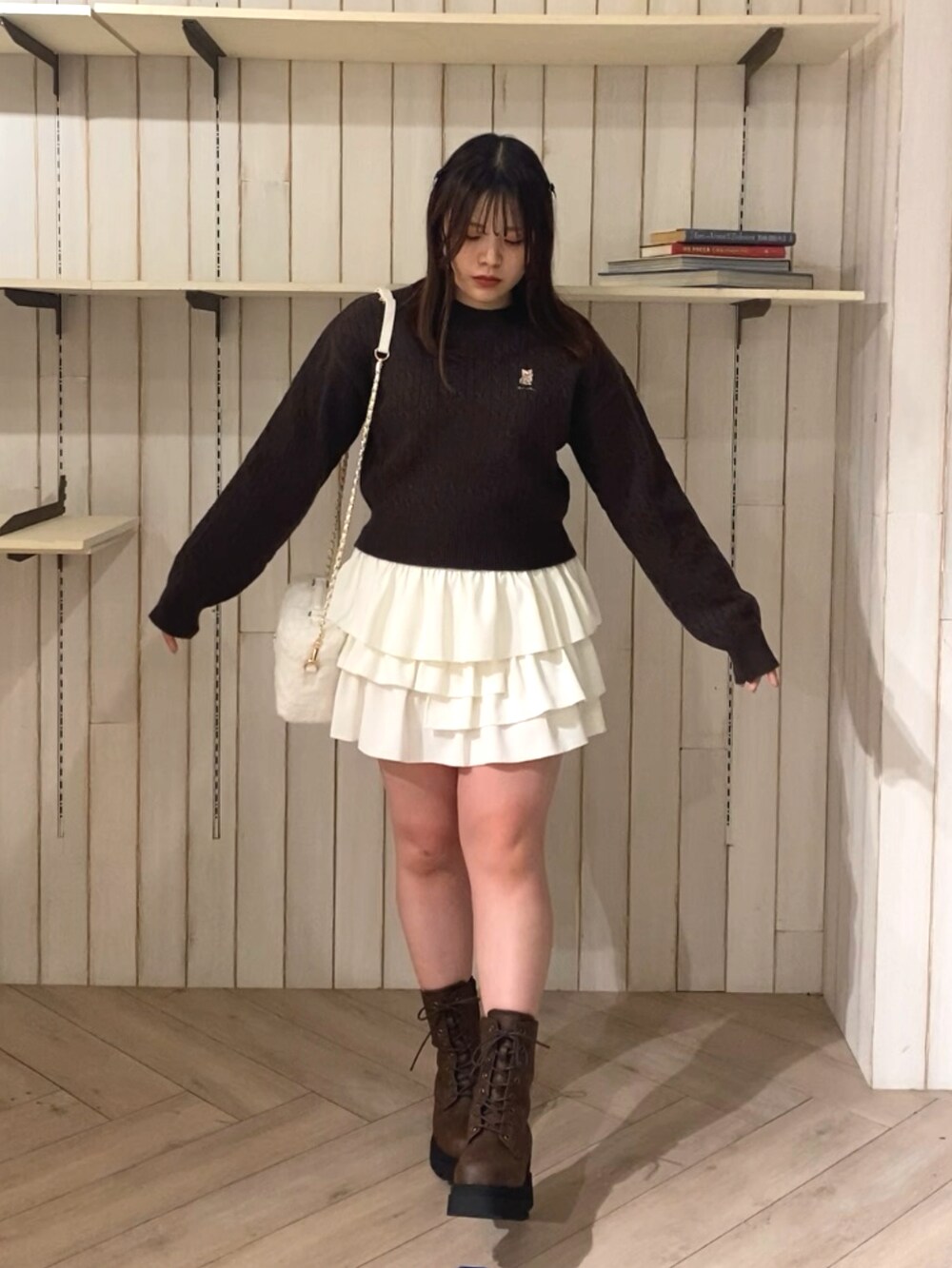 ブラウン系のニット/セーター、ホワイト系のスカート、ブラウン系のブーツを着用したレディースの秋コーディネートの2枚目の写真