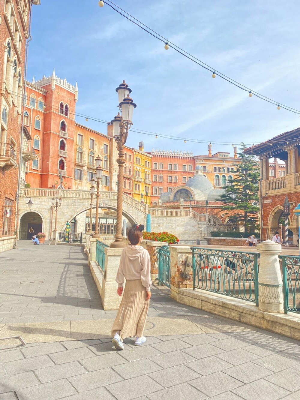 ベージュ系のトートバッグ、ピンク系のパーカー、ベージュ系のスカートを着用したレディースの春コーディネートの2枚目の写真