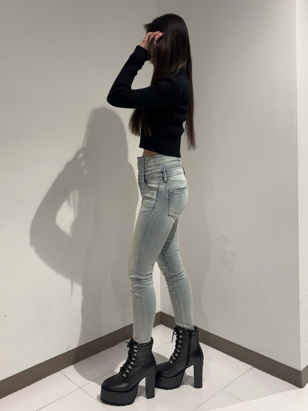 ブラック系のニット/セーター、ブルー系のデニムパンツ、ブラック系のブーツを着用したレディースの冬コーディネートの2枚目の写真