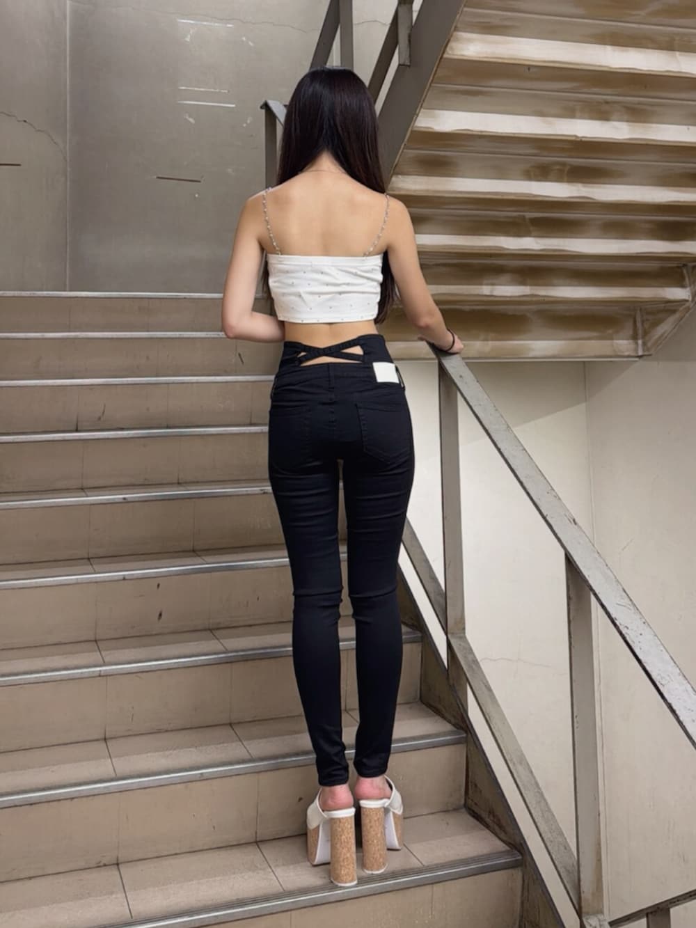 ホワイト系のサンダル、ホワイト系のキャミソール、ブラック系のデニムパンツを着用したレディースの夏コーディネートの3枚目の写真