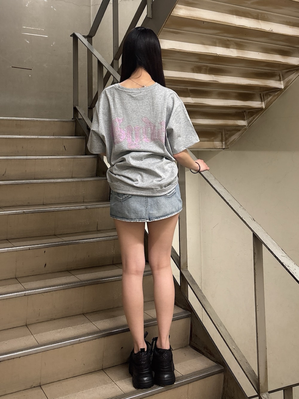 グレー系のTシャツ/カットソー、ブルー系のデニムスカート、ブラック系のスニーカーを着用したレディースの春コーディネートの3枚目の写真