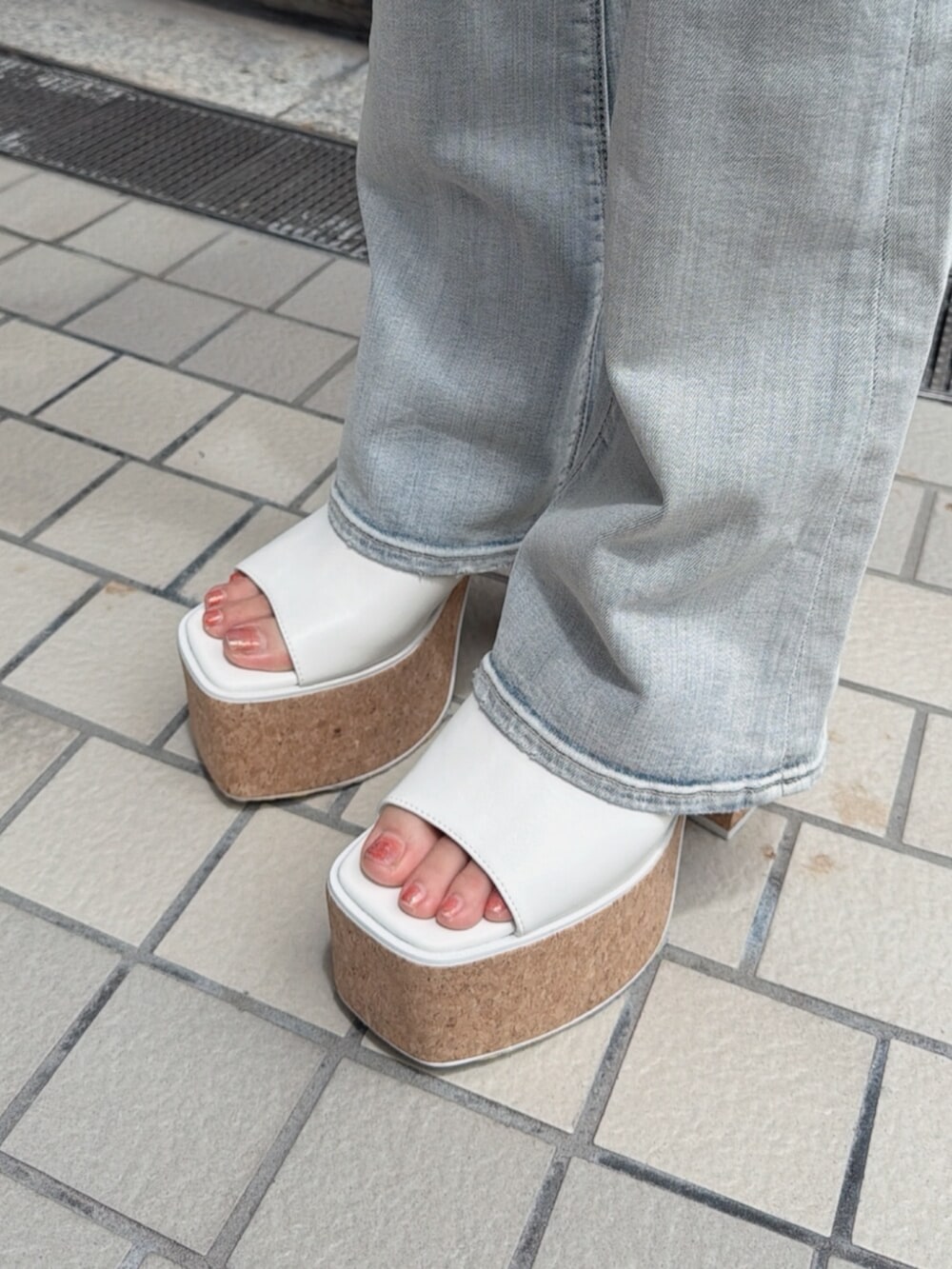 ホワイト系のサンダル、ブルー系のデニムパンツ、ブラック系のチューブトップを着用したレディースの夏コーディネートの4枚目の写真
