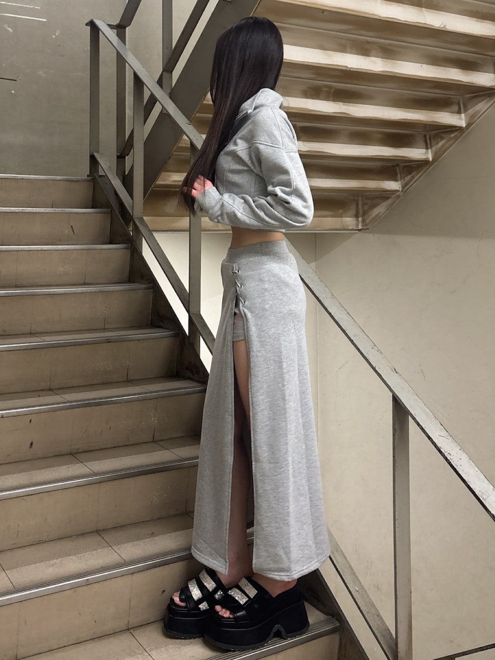 グレー系のスウェット、グレー系のスカート、ブラック系のサンダルを着用したレディースの冬コーディネートの2枚目の写真