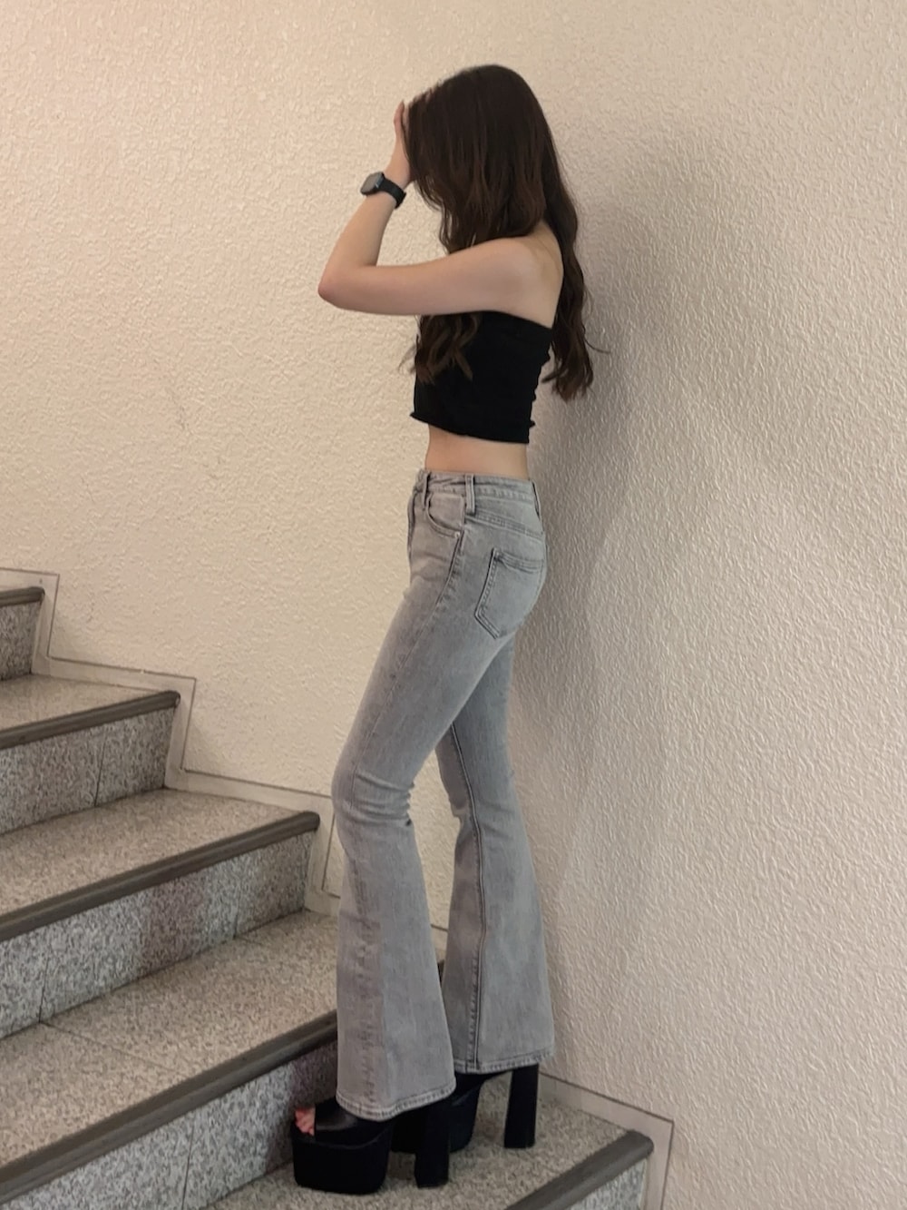 グレー系のデニムパンツ、ブラック系のサンダル、ブラック系のニット/セーターを着用したレディースの夏コーディネートの2枚目の写真