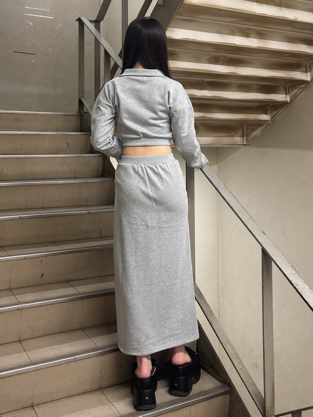 グレー系のスウェット、グレー系のスカート、ブラック系のサンダルを着用したレディースの冬コーディネートの3枚目の写真