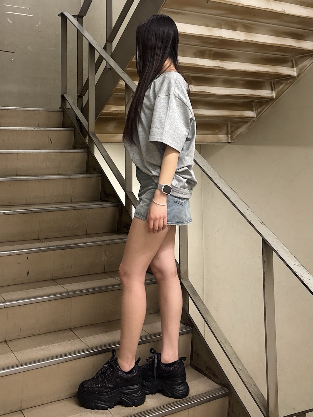 グレー系のTシャツ/カットソー、ブルー系のデニムスカート、ブラック系のスニーカーを着用したレディースの春コーディネートの2枚目の写真