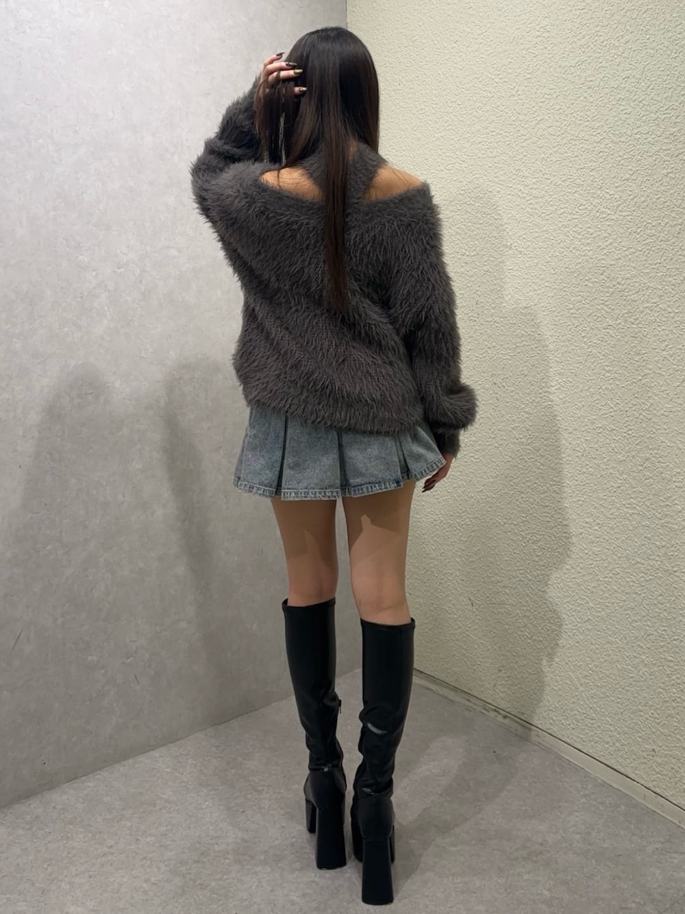 グレー系のニット/セーター、ブルー系のデニムスカート、ブラック系のブーツを着用したレディースの秋コーディネートの3枚目の写真