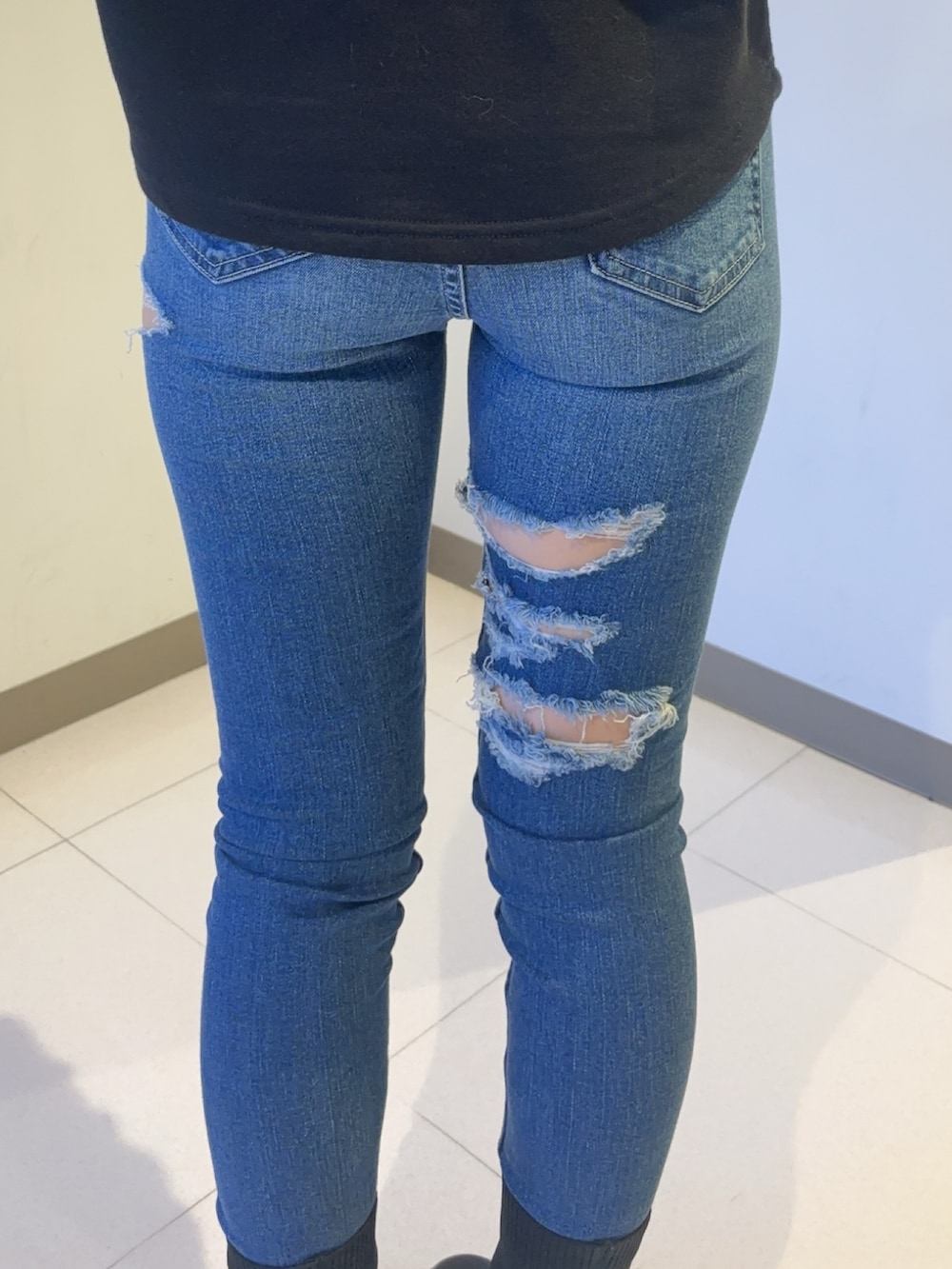 ブラック系のスウェット、ブルー系のデニムパンツ、ブラック系のブーツを着用したレディースの秋コーディネートの5枚目の写真