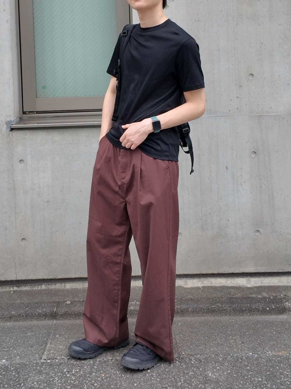 ブラウン系のスラックス、ブラック系のTシャツ/カットソー、ブラック系のバックパック/リュックを着用したメンズの夏コーディネートの2枚目の写真