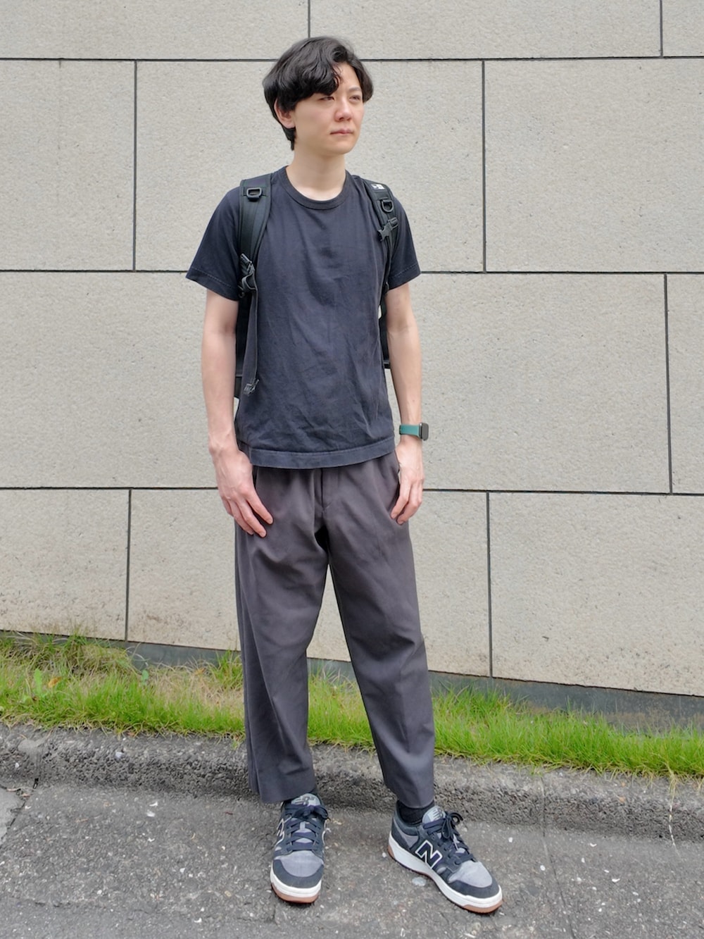 グレー系のパンツ、ブラック系のトップス、ブラック系のスニーカーを着用したメンズの夏コーディネートの2枚目の写真