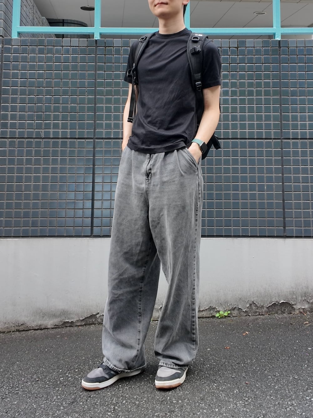 ブラック系のスニーカー、ブラック系のTシャツ/カットソー、ブラック系のバックパック/リュックを着用したメンズの秋コーディネートの2枚目の写真