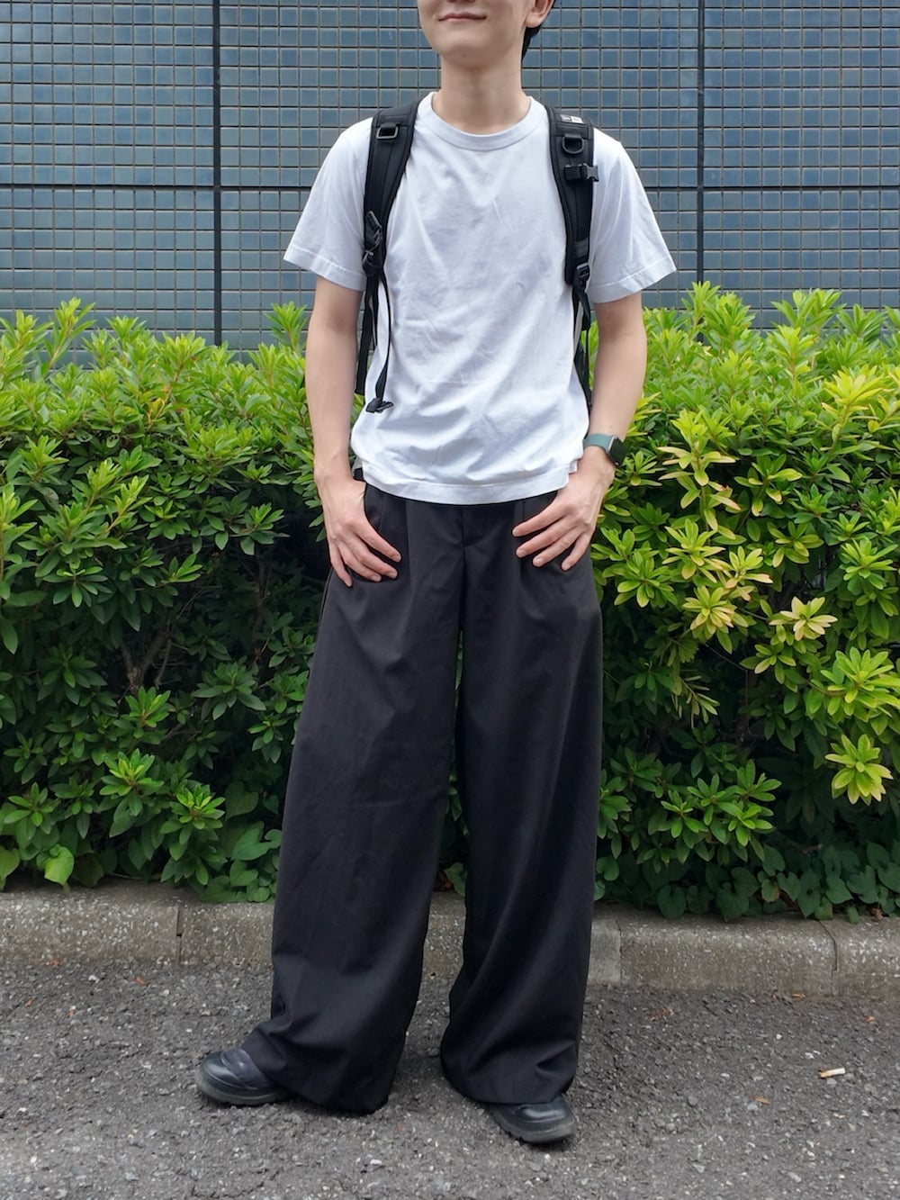 ブラック系のスラックス、ホワイト系のTシャツ/カットソー、ブラック系のバックパック/リュックを着用したメンズの夏コーディネートの2枚目の写真