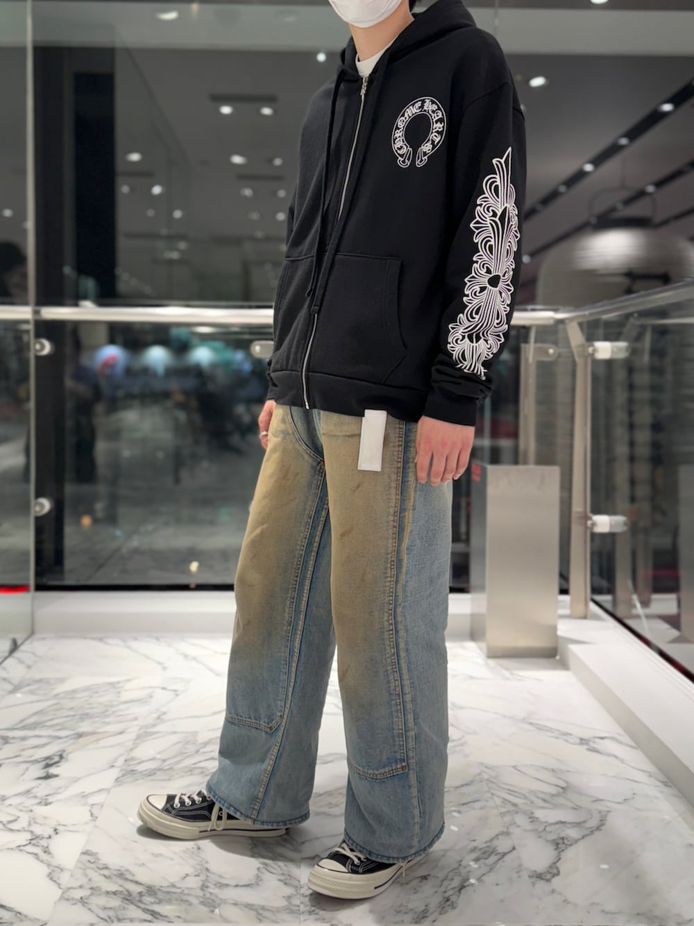 ブルー系のデニムパンツ、ブラック系のスニーカー、ブラック系のパーカーを着用したメンズの春コーディネートの2枚目の写真