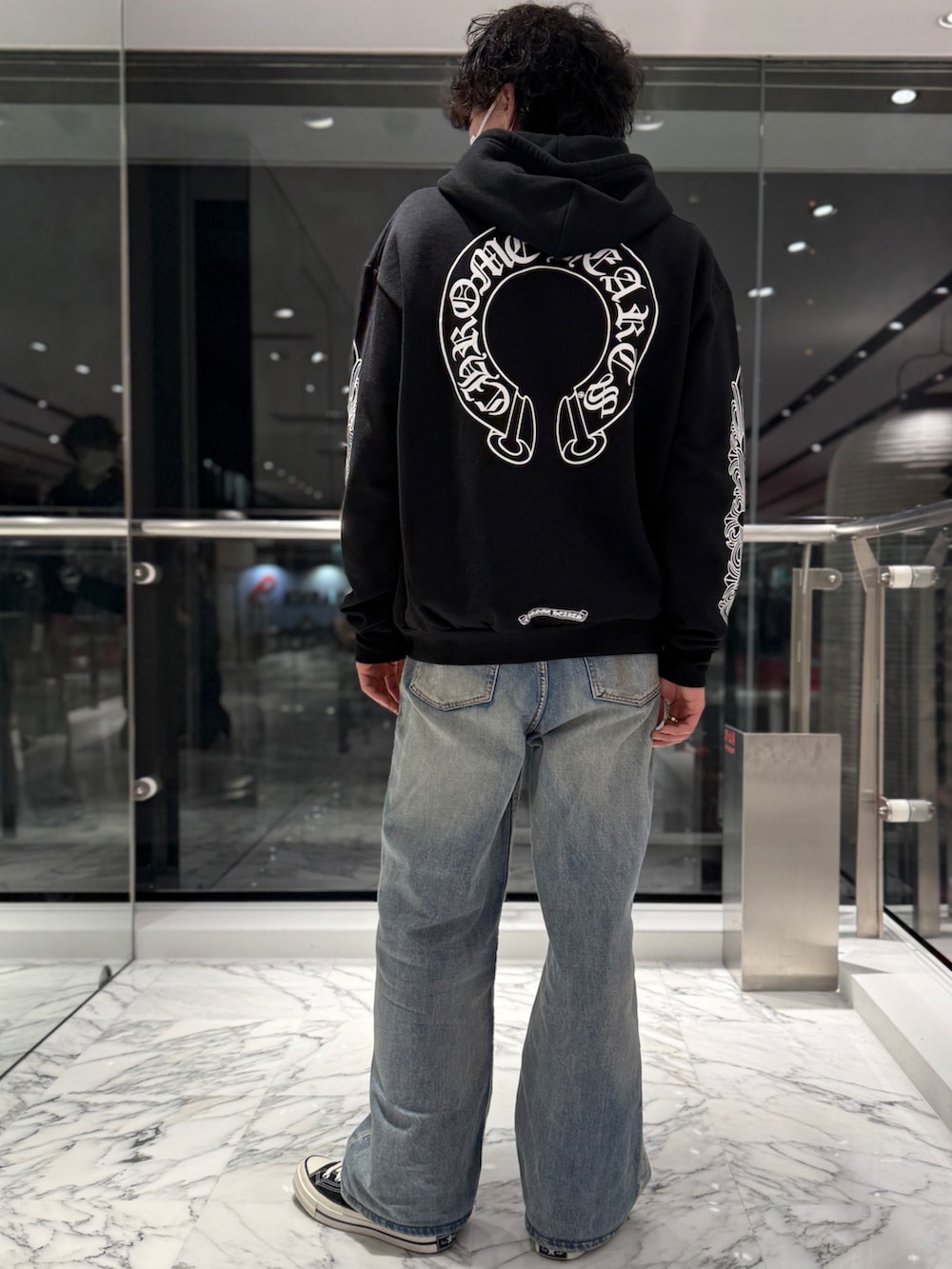 ブルー系のデニムパンツ、ブラック系のスニーカー、ブラック系のパーカーを着用したメンズの春コーディネートの3枚目の写真