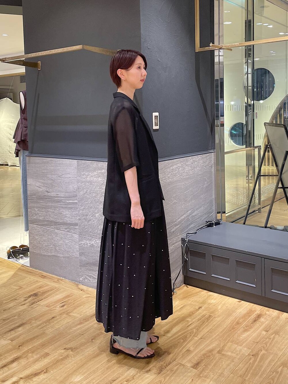ブラック系のワンピース、ブルー系のデニムパンツ、ブラック系のサンダルを着用したレディースの夏コーディネートの3枚目の写真
