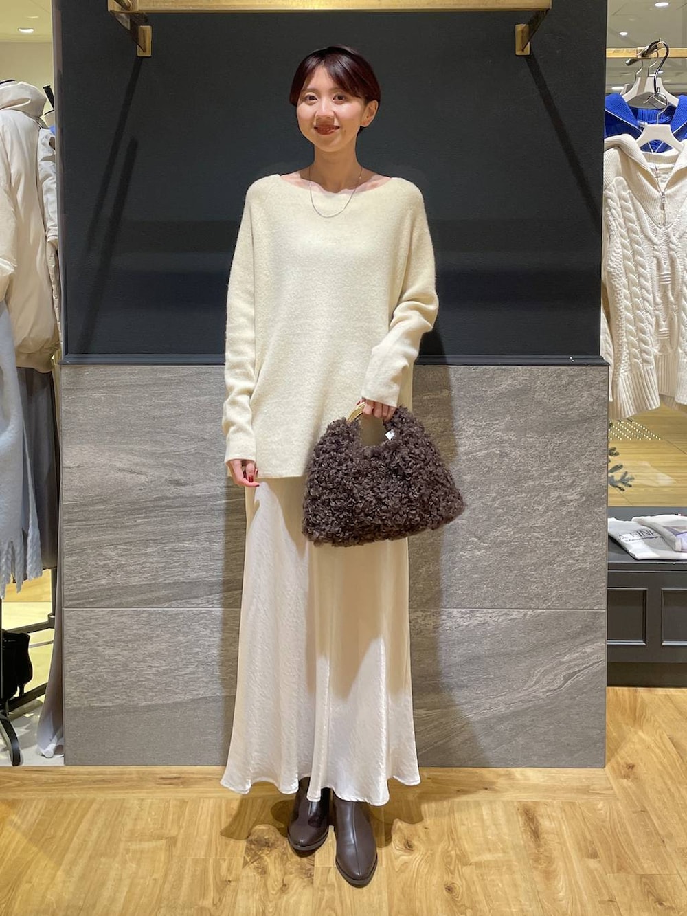 イエロー系のニット/セーター、ブラウン系のブーツ、ホワイト系のスカートを着用したレディースの秋コーディネートの3枚目の写真