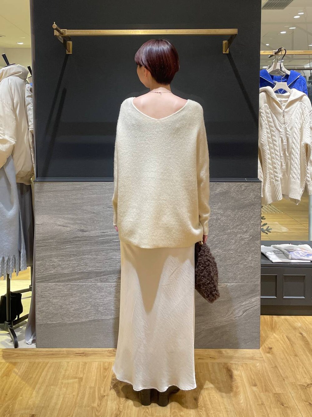 イエロー系のニット/セーター、ブラウン系のブーツ、ホワイト系のスカートを着用したレディースの秋コーディネートの5枚目の写真