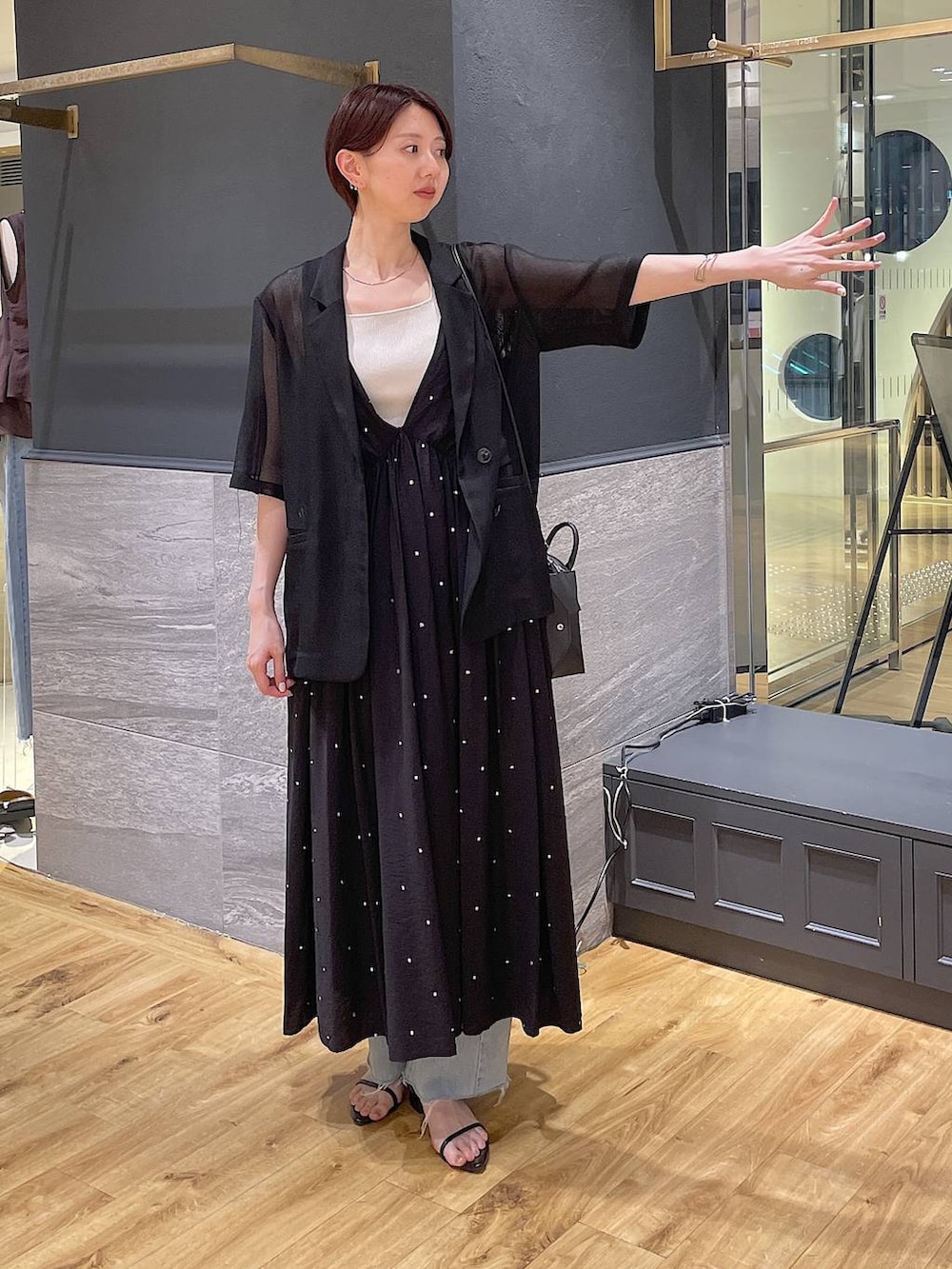 ブラック系のワンピース、ブルー系のデニムパンツ、ブラック系のサンダルを着用したレディースの夏コーディネートの2枚目の写真
