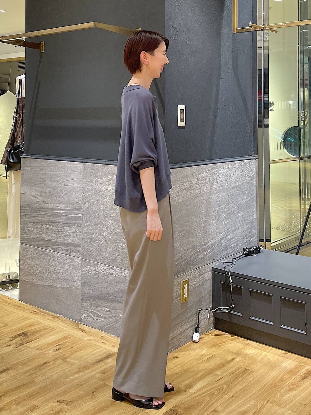 グレー系のニット/セーター、ブラック系のパンプス、ベージュ系のスラックスを着用したレディースの夏コーディネートの3枚目の写真