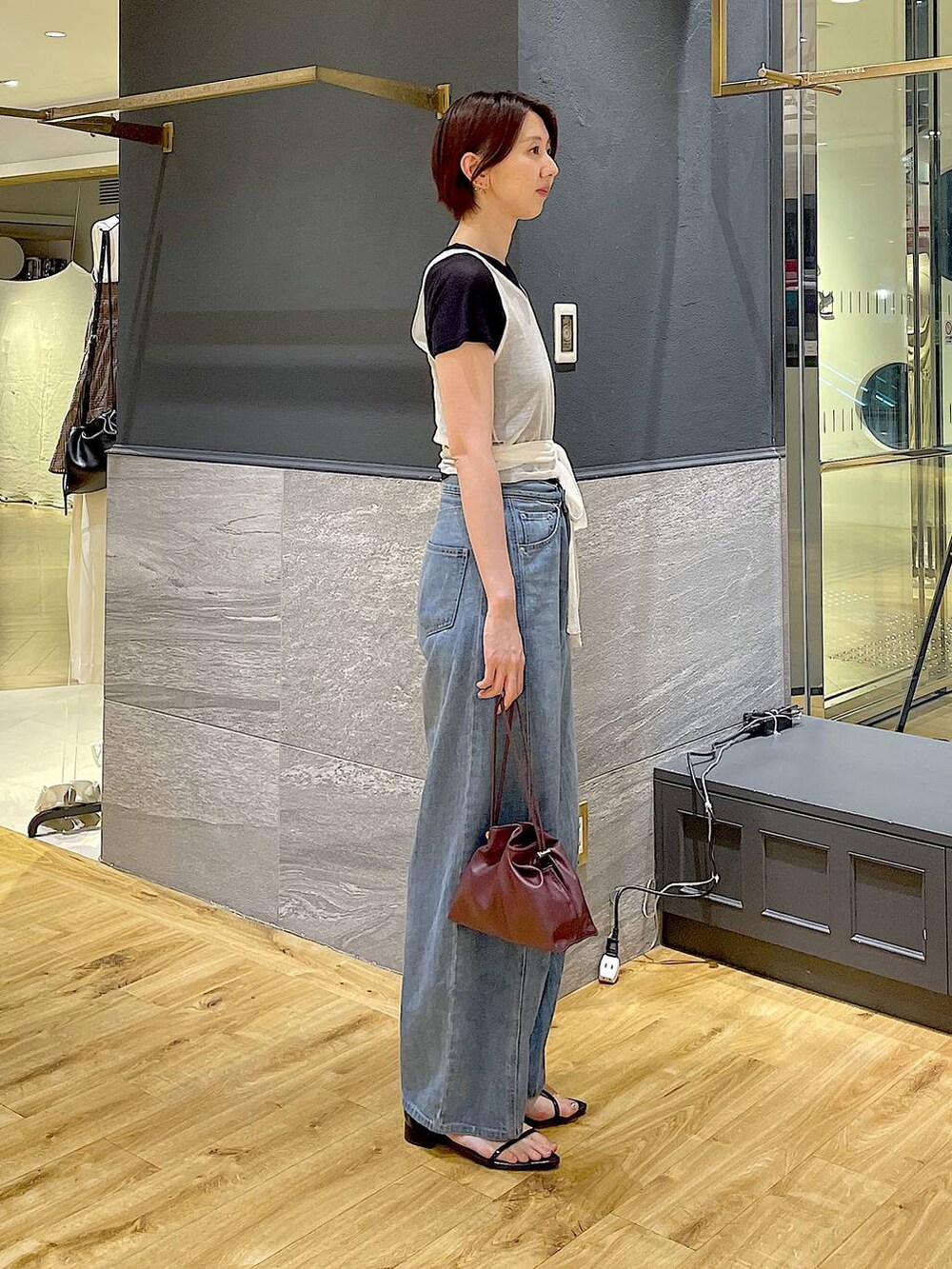 レッド系のショルダーバッグ、ブルー系のデニムパンツ、ブラック系のサンダルを着用したレディースの夏コーディネートの3枚目の写真