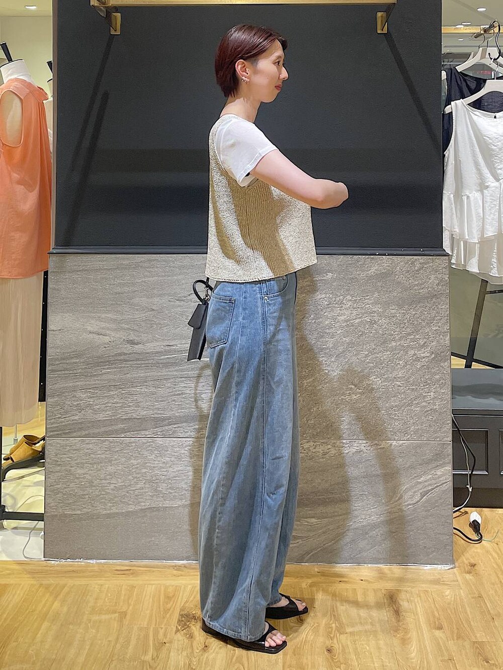 ブルー系のデニムパンツ、ブラック系のパンプス、ベージュ系のニット/セーターを着用したレディースの夏コーディネートの2枚目の写真