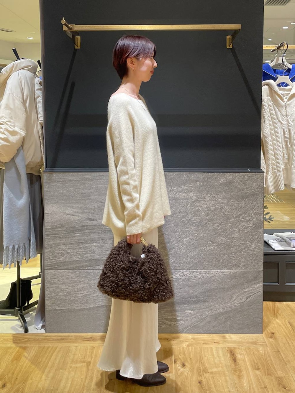 イエロー系のニット/セーター、ブラウン系のブーツ、ホワイト系のスカートを着用したレディースの秋コーディネートの4枚目の写真