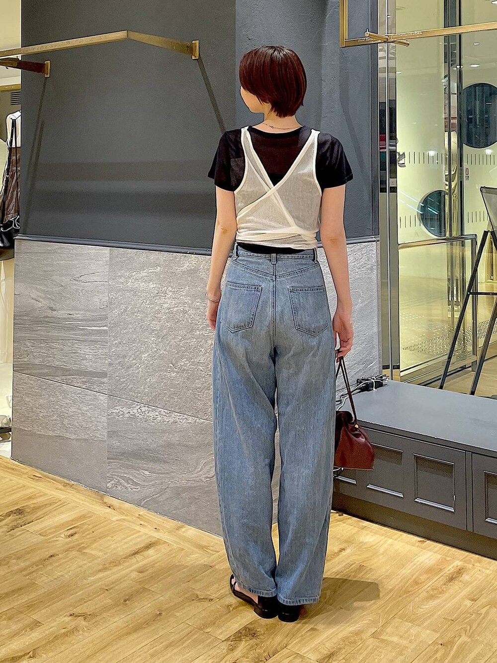 レッド系のショルダーバッグ、ブルー系のデニムパンツ、ブラック系のサンダルを着用したレディースの夏コーディネートの4枚目の写真