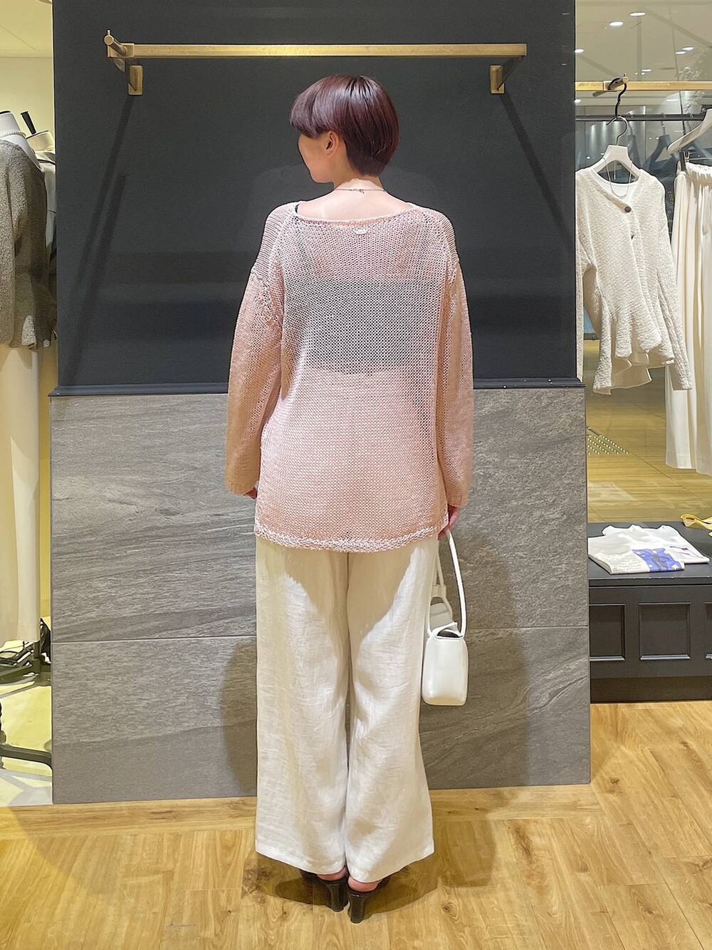 ブラック系のパンプス、ホワイト系のショルダーバッグ、ピンク系のニット/セーターを着用したレディースの春コーディネートの4枚目の写真