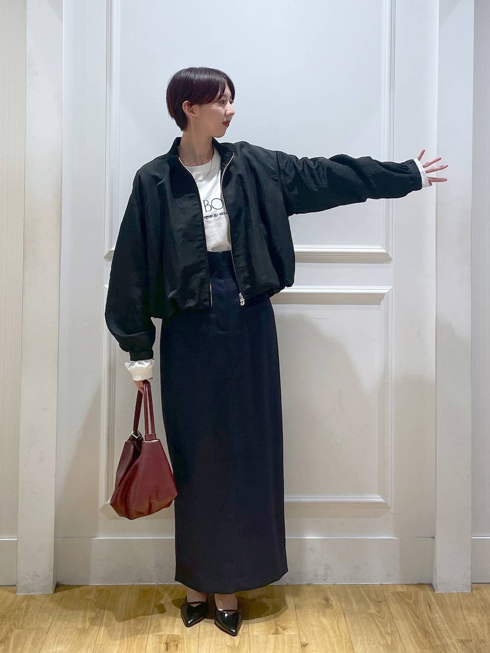 ブラック系のパンプス、ブルー系のスカート、ブラック系のブルゾンを着用したレディースの秋コーディネートの2枚目の写真