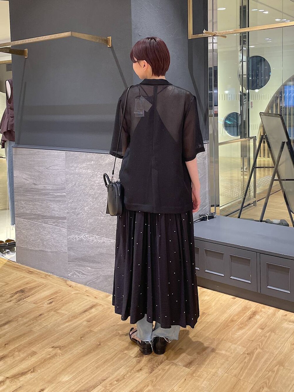 ブラック系のワンピース、ブルー系のデニムパンツ、ブラック系のサンダルを着用したレディースの夏コーディネートの4枚目の写真