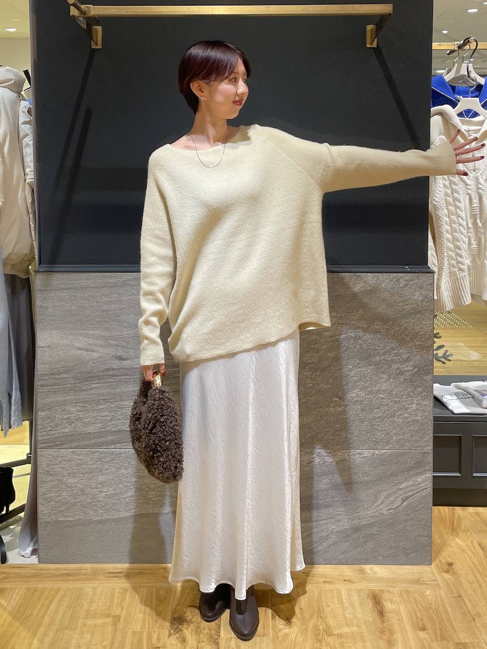 イエロー系のニット/セーター、ブラウン系のブーツ、ホワイト系のスカートを着用したレディースの秋コーディネートの2枚目の写真