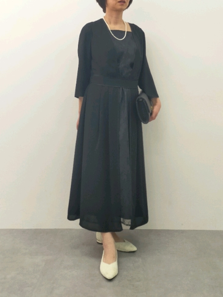 ブラック系のワンピース、ブラック系のバッグ、ブラック系のパンプスを着用したレディースの冬コーディネートの2枚目の写真